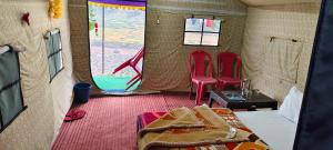 - une chambre avec 2 chaises rouges et un lit dans une tente dans l'établissement Barot , Waterfall Camps and Domes I Best seller, à Mandi