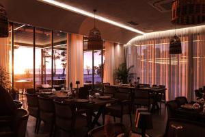 a dining room with tables and chairs and windows at Frojd Kune Resort & Beach Hotel in Shëngjin