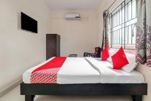 Un dormitorio con una cama con almohadas rojas y una ventana en 49996 JJ Comforts en Bangalore