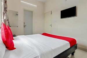 um quarto com uma cama branca e uma almofada vermelha em 49996 JJ Comforts em Bangalore