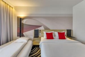 2 Betten in einem Hotelzimmer mit roten Kissen in der Unterkunft Novotel Köln City in Köln
