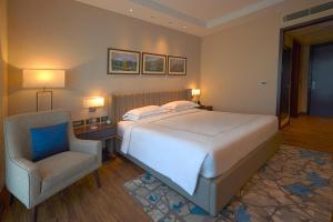 a bedroom with a large bed and a chair at Taj Bangalore in Devanahalli-Bangalore