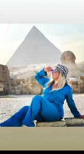 a woman sitting on a ledge in front of the pyramids at Horus pyramids Palace in Cairo