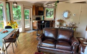 ein Wohnzimmer mit einem Ledersofa und einem Tisch in der Unterkunft Chalet 141 - Peaceful wooded views cozy interiors plus wifi in Marblehill