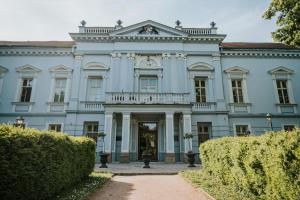 una gran mansión azul con arbustos delante en Hotel Kaštieľ Mojmírovce en Mojmírovce