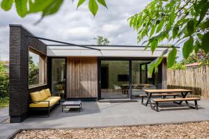 a patio with a couch and a table at Stijlvol ingerichte (4 pers.) bungalow in Baarland in Baarland