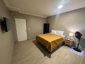 ein Schlafzimmer mit einem Bett mit gelber Bettdecke und einer Lampe in der Unterkunft Villa Sicilia in Guatemala
