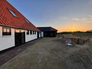 a barn with a building and a bench in a field at In de duinen in De Koog