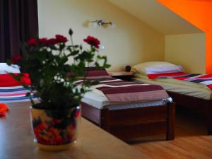 a room with two beds and a vase with red roses at DW Poronianka in Poronin