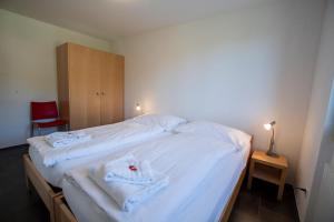 a bedroom with a white bed with towels on it at Haus Bella Vista in Riederalp