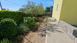 a garden next to a building with bushes and a sidewalk at Apartments Jana in Krk