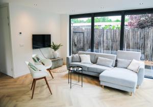 un soggiorno con divano, sedie e TV di Stijlvol ingerichte (4 pers.) bungalow in Baarland a Baarland