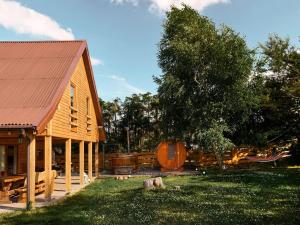 a wooden cabin with a tree and a barrel at Holiday Home Nadole near Baltic Sea in Nadole