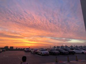 a parking lot with cars parked in front of a sunset at Xi'an Xianyang International Airport Space Capsule Hotel in Xi'an