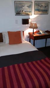 een slaapkamer met een bed en een bureau met een lamp bij Albertinia Hotel in Albertinia