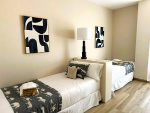 瓦倫西亞的住宿－Pont de Fusta Apartments，一间卧室设有两张床,墙上挂有绘画作品
