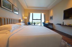 a hotel room with a large white bed with a window at Taj Bangalore in Devanahalli-Bangalore