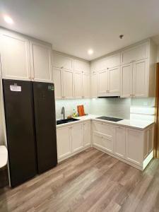 a kitchen with white cabinets and a black refrigerator at Sora House 5 - Vinhomes Ocean Park in Gia Lâm Pho