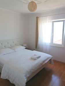 sypialnia z dużym białym łóżkiem i oknem w obiekcie Apartments Dinko w Duće
