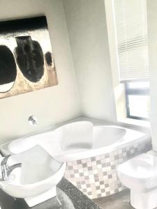 a bathroom with a tub and a toilet and a sink at 3 Indigo in Hermanus