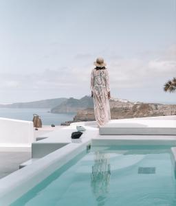 una mujer con un vestido de pie junto a una piscina en Nelya Suites en Megalokhori
