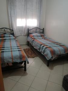 2 Betten neben einem Fenster in einem Zimmer in der Unterkunft Avito maroc in Oulad Yakoub