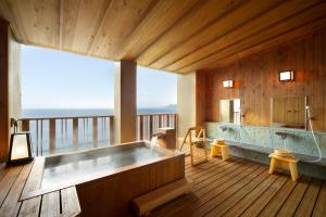 a bath tub in a room with a view of the ocean at Senoumi in Higashiizu