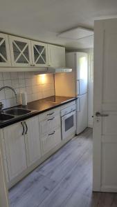 cocina con armarios blancos, fregadero y nevera en Minivilla in Gustavsvik Nacka, en Gustavsvik