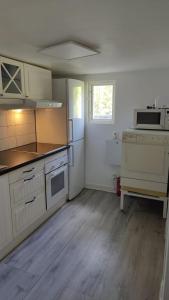 cocina con armarios blancos y nevera blanca en Minivilla in Gustavsvik Nacka, en Gustavsvik