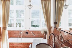 ein Bad mit einer Badewanne und Fenstern in der Unterkunft Relais & Chateaux Hotel Castel Fragsburg in Meran
