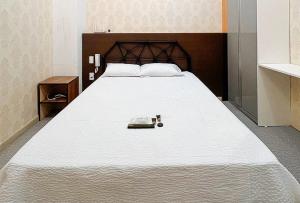 ein großes weißes Bett mit einem Kopfteil aus Holz in der Unterkunft RedDoorz Premium at Regency Sunset Hotel in Angeles