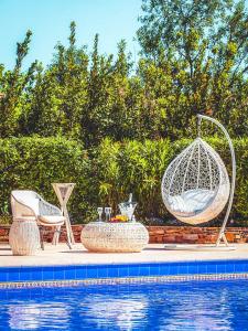 a swimming pool with two chairs and a hammock next to a swimming pool at Hôtel La Mandarine in Saint-Tropez
