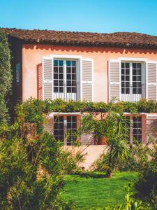 a pink house with white windows and a yard at Hôtel La Mandarine in Saint-Tropez