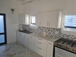 a kitchen with white cabinets and a stove at Holiday Beach House in Velddrif