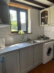 a kitchen with a sink and a washing machine at The Stables, Moulton St Mary in Norwich