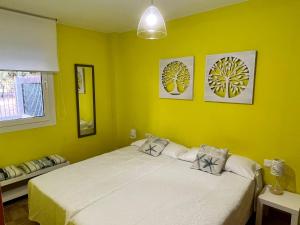 - une chambre avec un grand lit aux murs jaunes dans l'établissement UMA luna al sol Benicarlo-Peñiscola, à Benicarló