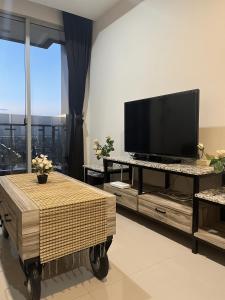 un soggiorno con TV a schermo piatto su un tavolo di DeAr Caspian Apartment a Surabaya