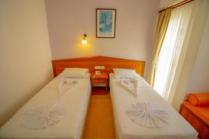 a room with two beds and a table and a window at Celeste Hotel in Fethiye