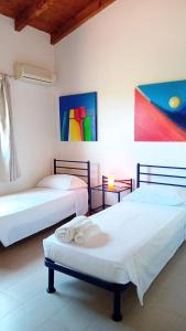 two beds in a room with paintings on the wall at Villa Serena A in Stintino +10 photos