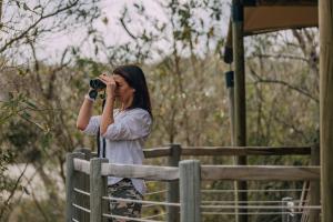 Eine Frau fotografiert einen Zaun mit einer Kamera. in der Unterkunft Mdluli Safari Lodge in Hazyview