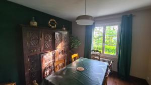 a dining room with a table and a large wooden cabinet at LA TANIÈRE in Gueures