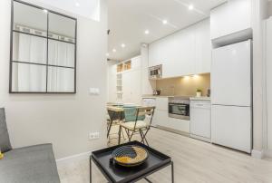 une cuisine avec des placards blancs et une table dans l'établissement Apartamento Bernabeu Comfort en Madrid, à Madrid