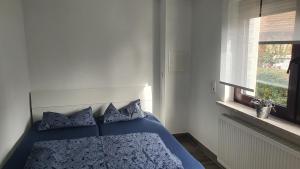 a bedroom with a blue bed with pillows and a window at FeWo Drei Gleichen- Nr2 in Wandersleben