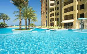 a large swimming pool with palm trees and buildings at Dream Inn Apartments - Luxury 2BR in Marjan Island Close to Beach in Ras al Khaimah