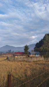 a fence in a field with a barn in the background at Arunachal Guest house in Hāpoli