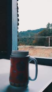 Arunachal Guest house في Hāpoli: كوب قهوة احمر على حافة النافذة
