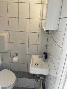 La salle de bains est pourvue de toilettes blanches et d'un lavabo. dans l'établissement Apartmenthaus am Rennplatz, à Brême