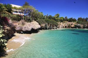 a beach with turquoise water and trees and a building at Elio A 1BDR Apt with Garden 1 min from the beach by Hospi in Heraklio Town