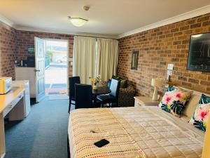 a hotel room with a bed and a table and chairs at Town and Country Motor Inn in Tamworth