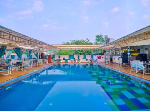 a large swimming pool with chairs and tables at Sayaji Pune in Pune